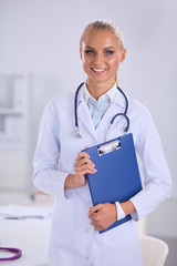 Smiling female doctor with a folder in uniform standing at