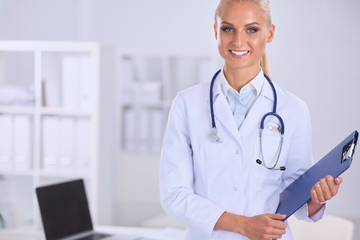 Smiling female doctor with a folder in uniform standing at