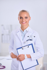 Smiling female doctor with a folder in uniform standing at