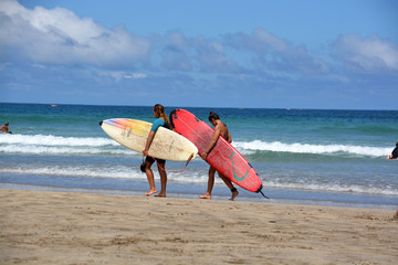 dos surfistas caminando por la playa