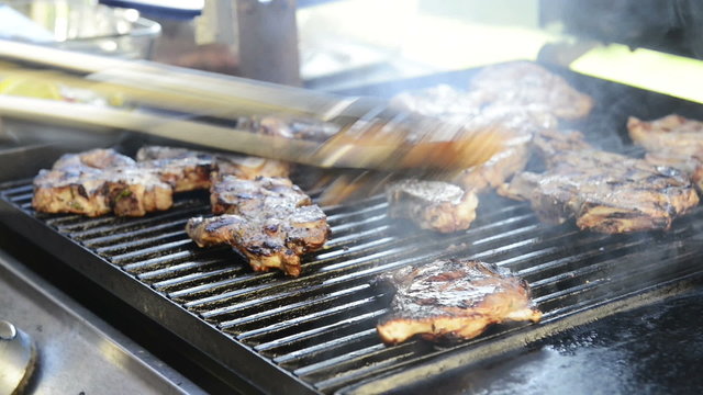 A man grills lamb chops on the outdoor barbecue