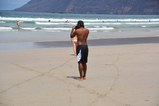 hombre fotografiando en la playa de famara de lanzarote
