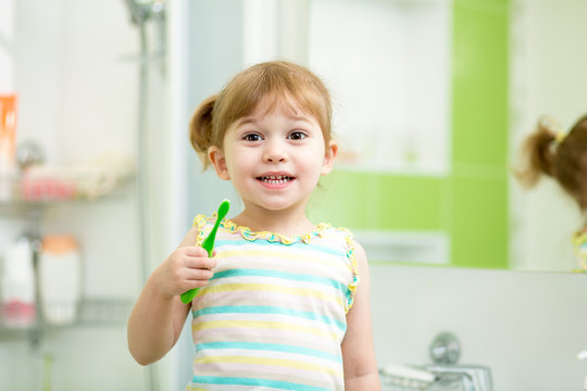 Child kid girl brushing teeth in bathroom