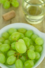 Selective focus of a single grape over a bowl of grapes