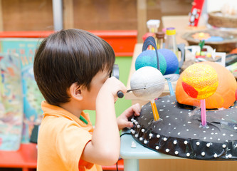 Little boy learning  looking into space in class room