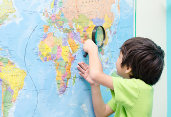 Little boy using magnify looking on map