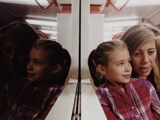 Mother and daughter reflected in a train mirror
