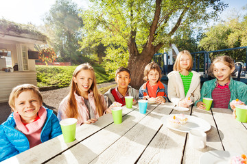 Happy group of children sitting at table outside