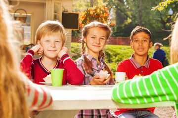 Happy kids drinking tea with cupcakes sitting