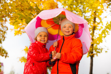 Boy and girl hold umbrella together under rain