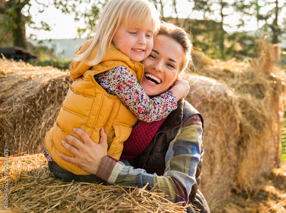 Wall mural portrait of happy mother and child hugging while on haystack