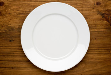 Empty white plate on wooden table