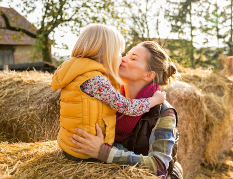 Portrait Of Mother And Child Kissing While Sitting On Haystack