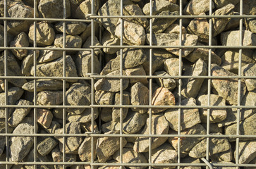 Wall of steel and stones in sunlight