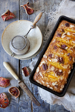 orange plumcake with pecan walnuts on mold on rustic table