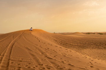 Fototapeta na wymiar Photo of local resident praying on a dune of a desert in the Uni