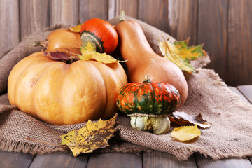 Pumpkins on sackcloth on wooden table on wooden wall background