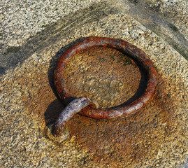 rusty mooring ring tied with pier stone
