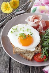 Fried egg with fresh bread,prosciutto,arugula and tomatoes