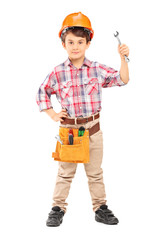 Cute little boy wearing working clothes and holding a wrench