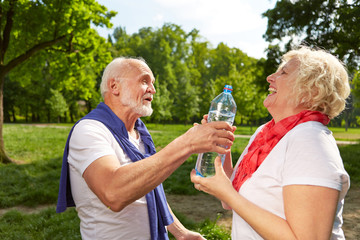 Lachende ältere Frau trinkt Wasser
