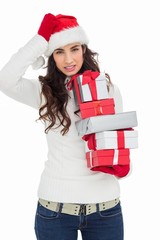 Stressed brunnette in santa hat holding gifts