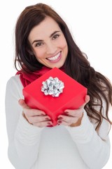 Happy brunette showing red gift with a bow