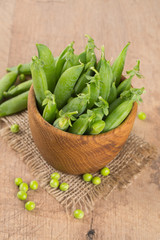 fresh pea pods in a wooden bowl