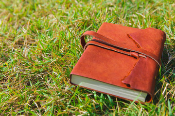Brown leather note book on green grass