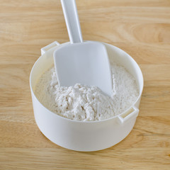 Bread flour with rubber scraper on wood table with equipment rea