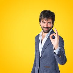 Businessman making Ok sign over yellow background