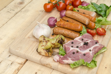 Fresh meat sausages  and vegetables on kitchen board
