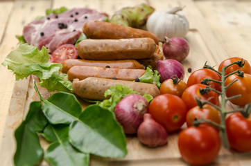 Fresh meat sausages  and vegetables on kitchen board
