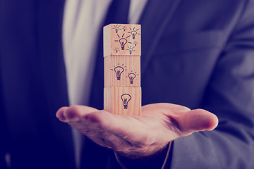 Businessman holding cubes with drawn light bulbs