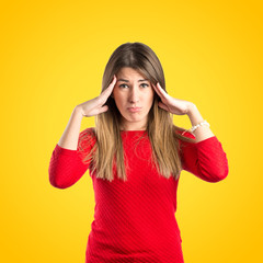 Cute girl with headache over yellow background