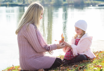 Fototapeta premium Little girl with her mother on the autumn lake