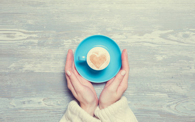 Female hand holding cup of coffee.