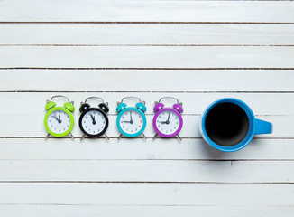Four alarm clocks and cup of coffee
