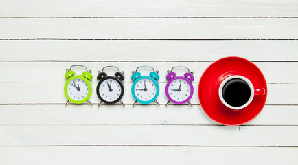 Four alarm clocks and cup of coffee