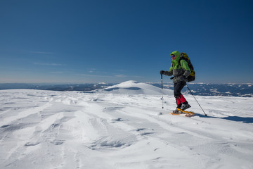 Fototapeta na wymiar Hiker snowshoeing in winter mountains during sunny day