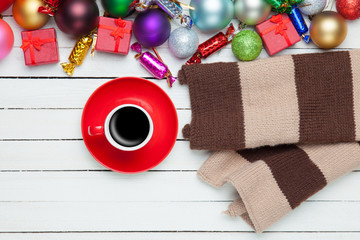 Red cup of coffee and scarf with christmas toys.
