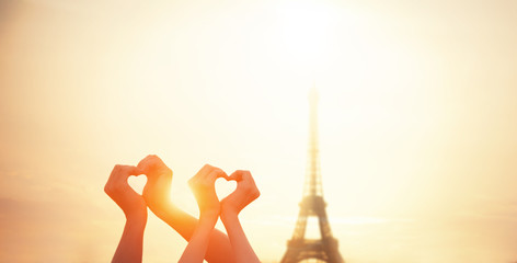 Two lovers showing heart shapes with hands and parisian Eiffel t