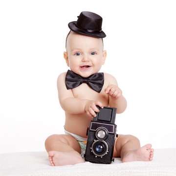 Baby boy plays with vintage camera against white background