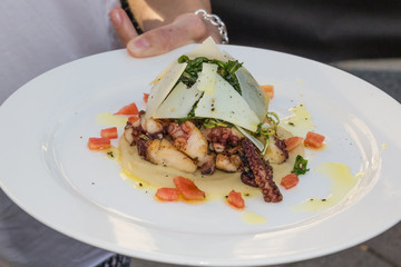 Waiter serving platter of fish and octopus