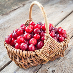 Fresh red cranberries in wicker basket on rustic table