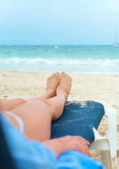 Fototapeta na wymiar Young woman sunbathing on lounger. Legs.