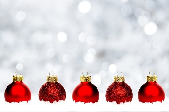 Christmas border of red baubles in snow with silver background