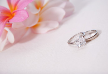 Two wedding rings in front of tropical flowers