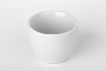 Small white empty cup with soft shadow stands on the table, sele