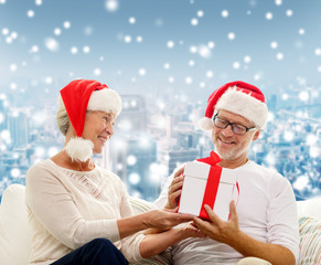 happy senior couple in santa hats with gift box